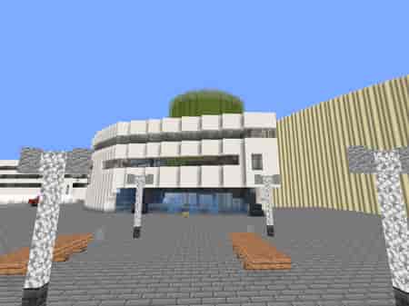 Minecraft render shown in browser depicting: The RGU Sir Ian Wood building entrance from street view with street lights and wooden benches.